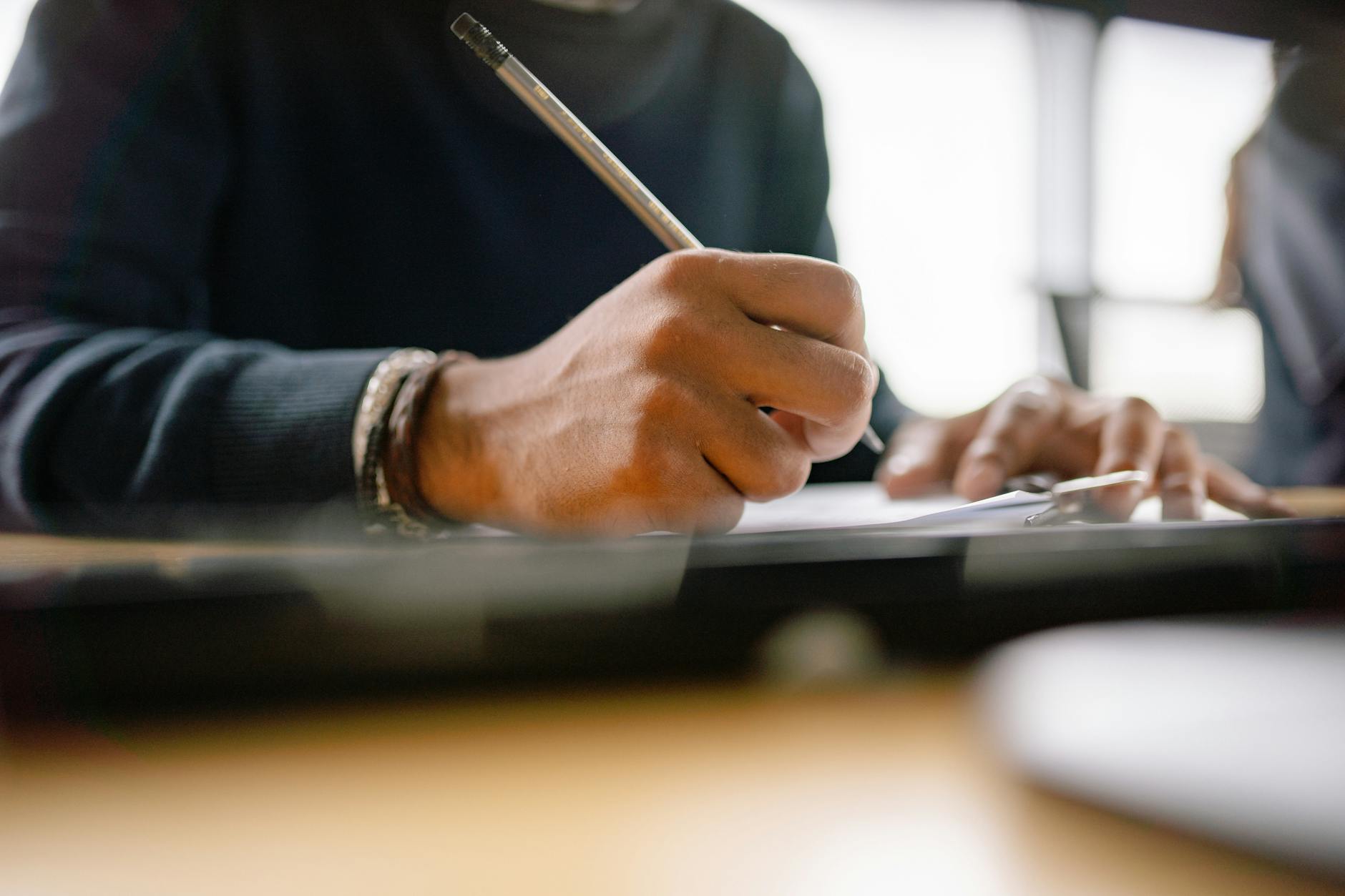 Dłoń z ołówkiem robi notatki na kartce podczas nauki angielskiego