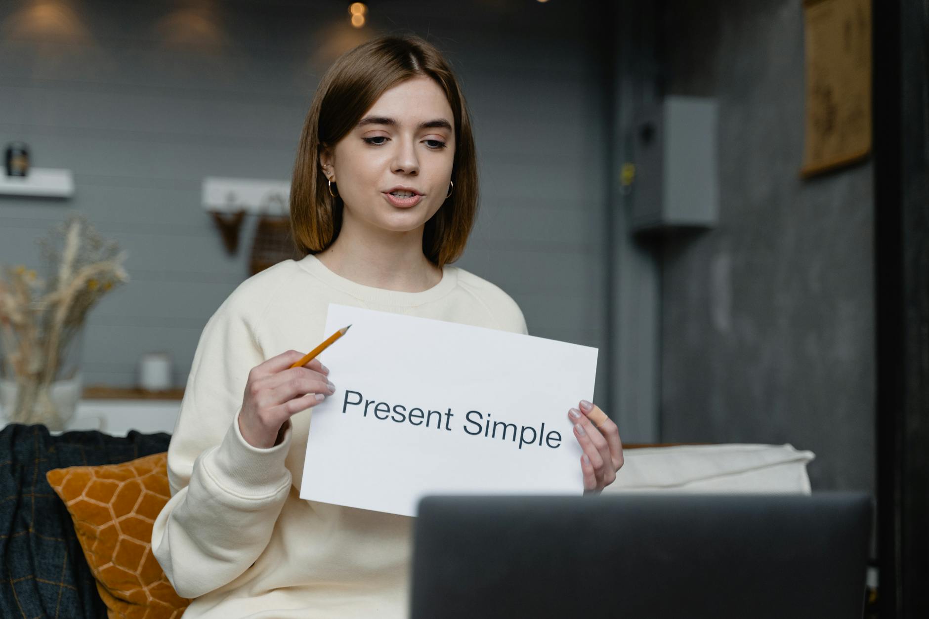 Młoda kobieta uczy online angielskiego czasu Present Simple