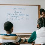 Angielskie liczby od 1 do 100: jak mówić i pisać bez pomyłek Nauczycielka matematyki tłumaczy liczby na tablicy uczniom w klasie