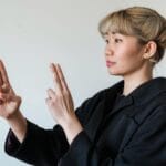 Azjatka pokazująca gesty języka migowego na białym tle