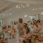 Mężczyzna wygłasza przemówienie na przyjęciu weselnym wśród gości