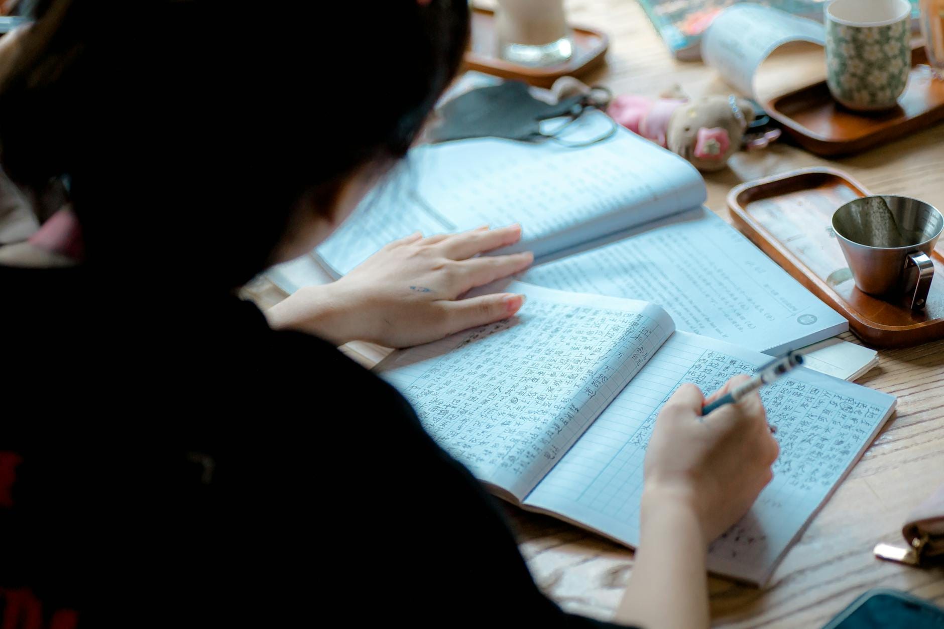 Skuteczne powtórki: kiedy i jak wracać do materiału, by go pamiętać Osoba robi notatki przy biurku podczas nauki języka angielskiego