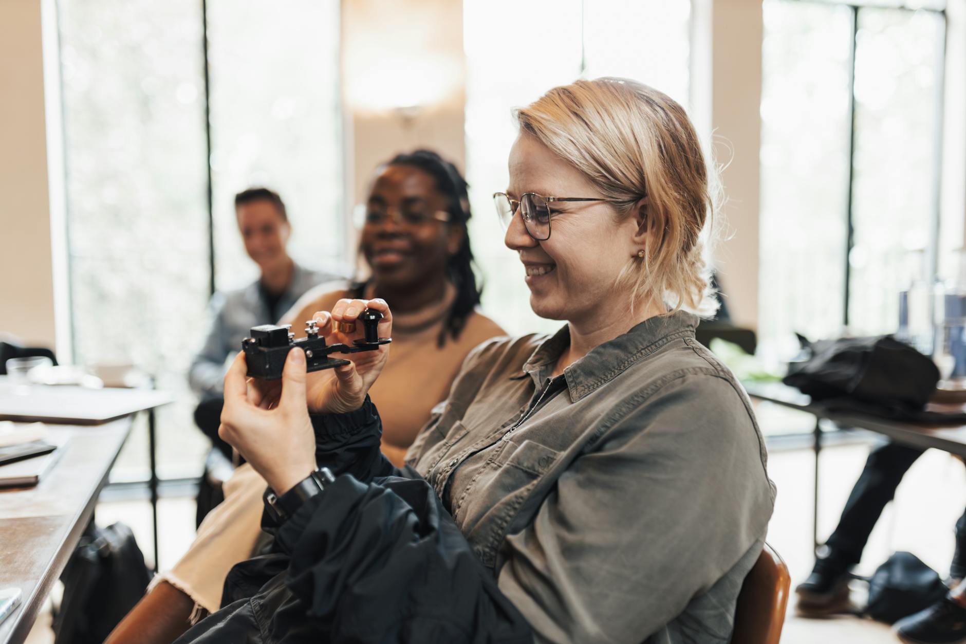Uśmiechnięta kobieta trzyma urządzenie VR w jasnym pomieszczeniu