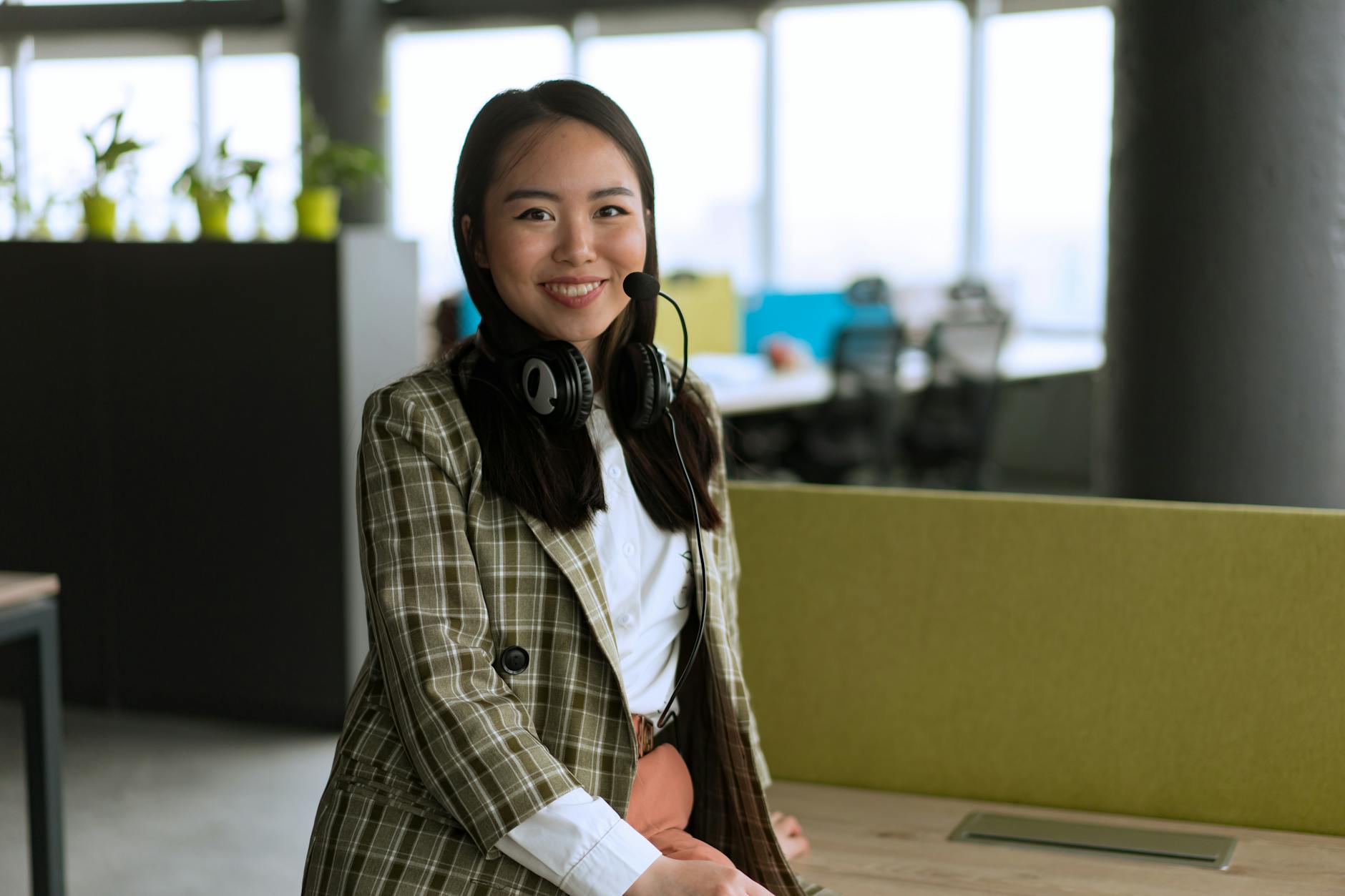 Kobieta w biurze ze słuchawkami na uszach uczy się angielskiego z muzyki