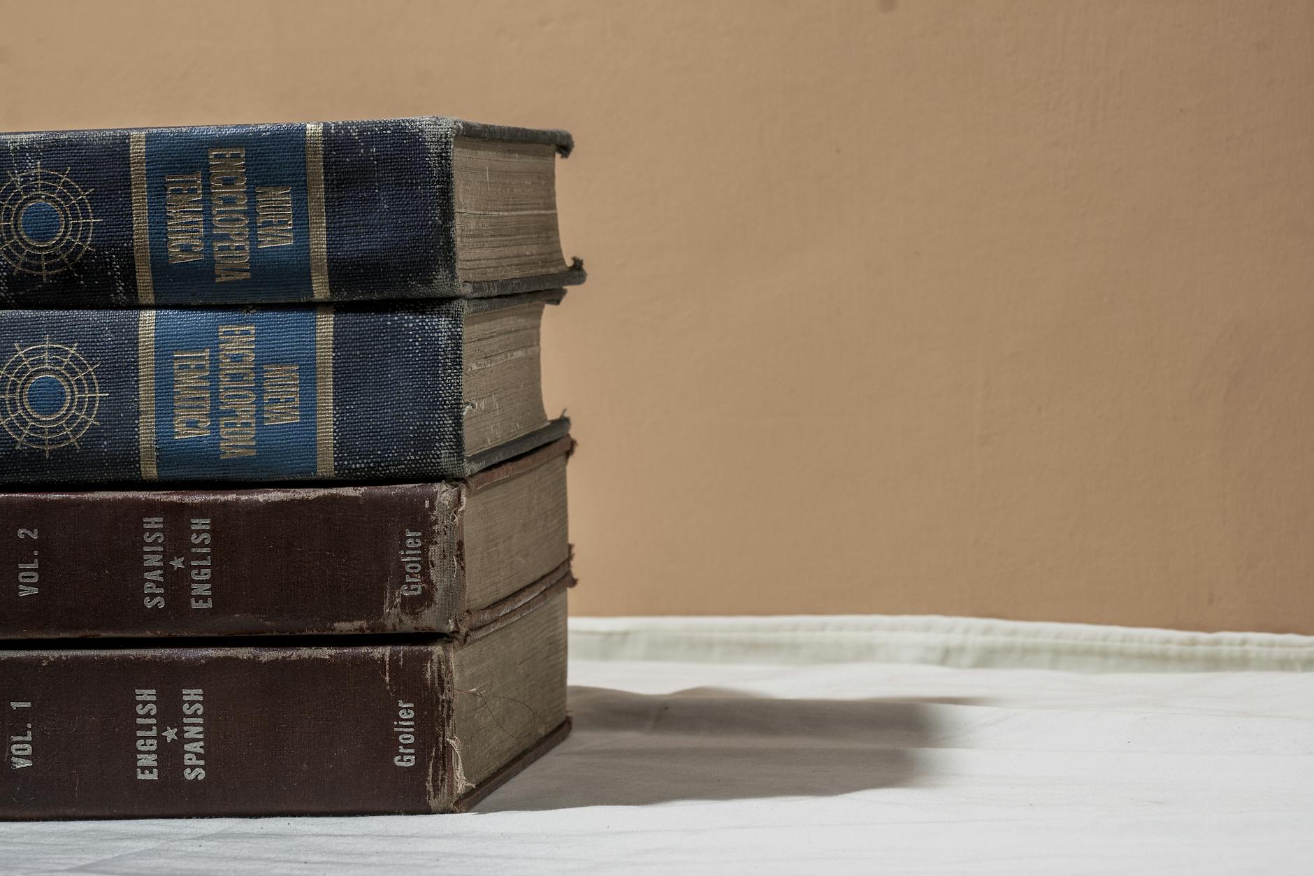 Stos encyklopedii i słowników na neutralnym tle